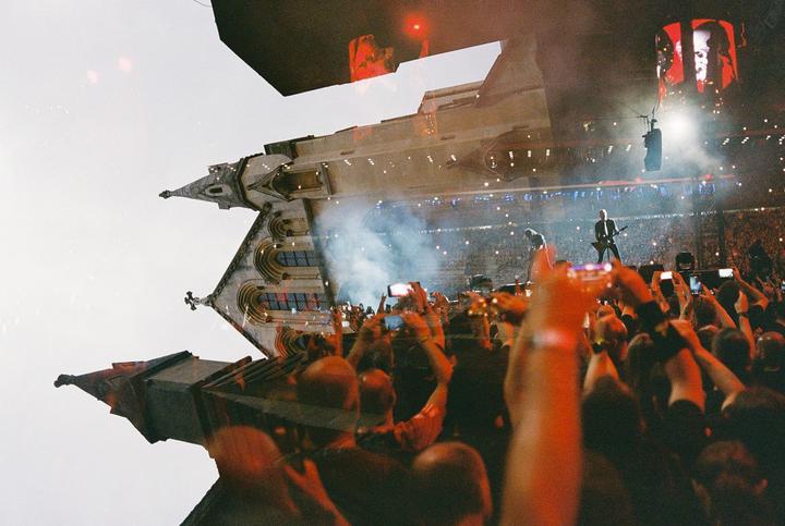 A double exposure shows a concert crowd with a musician on stage overlaid with a gothic building.