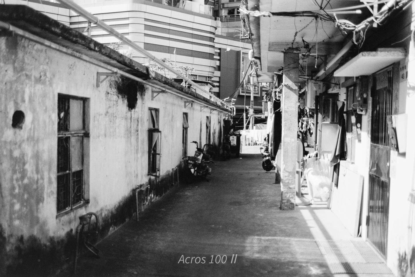 A narrow alleyway with old buildings on both sides and a modern building in the background.