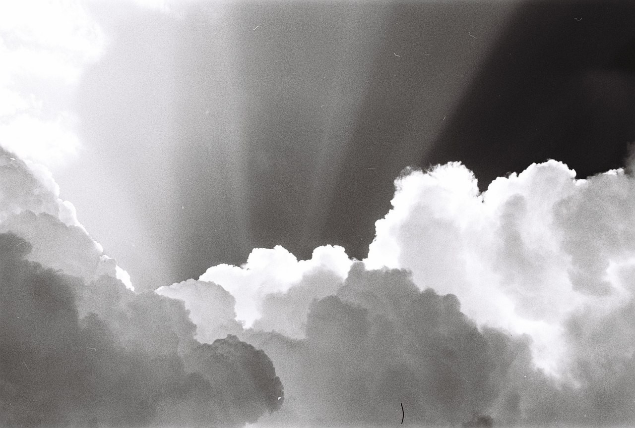Sunlight streams through a dramatic sky filled with large, fluffy clouds.