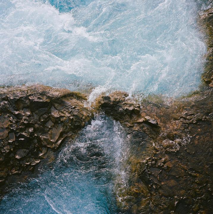 Water rushes over and around rocks in a river.