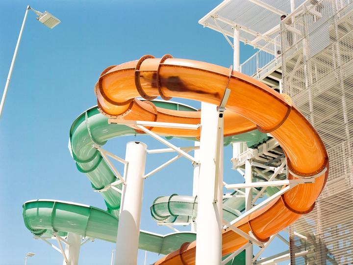 Two colorful water slides twist and turn against a clear blue sky.