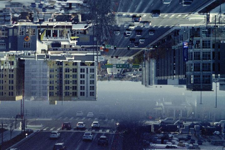 A double exposure shows a street with cars and buildings, with one exposure inverted.