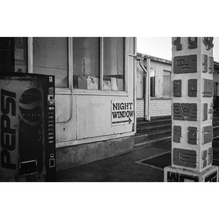 A Pepsi vending machine stands next to a building with a "Night Window" sign and a decorative pillar.