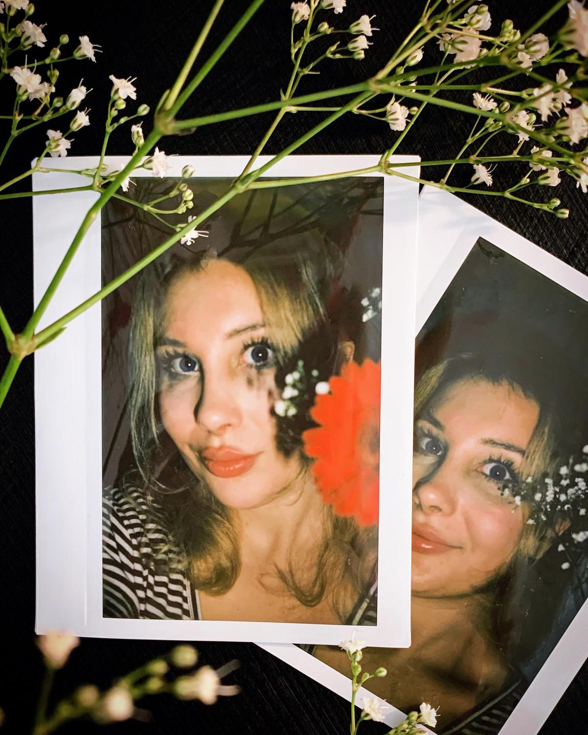 Two instant prints of a woman with flowers are arranged on a dark surface.