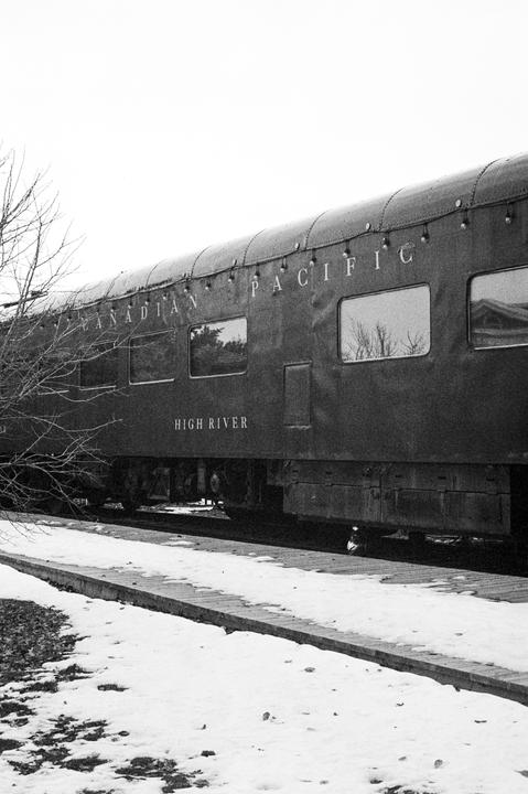 A train car with "Canadian Pacific" and "High River" written on its side is parked next to a snowy platform.