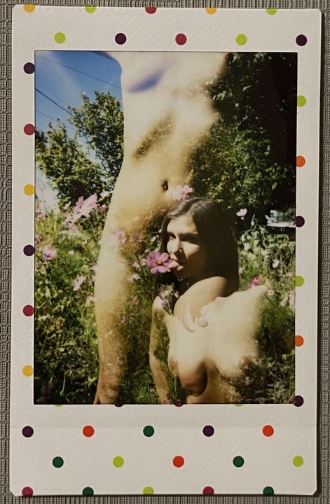 A double exposure shows a woman with a flower in her mouth and a partial nude body in a garden.
