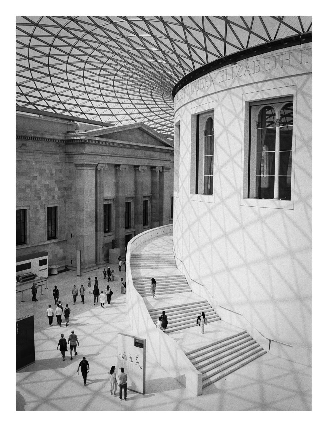 A large hall with a glass domed ceiling and a grand staircase is filled with people.