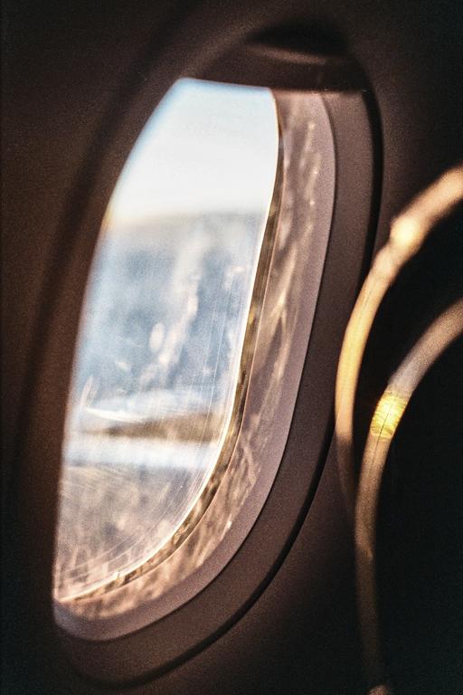 Sunlight streams through the window of an airplane, illuminating the interior.