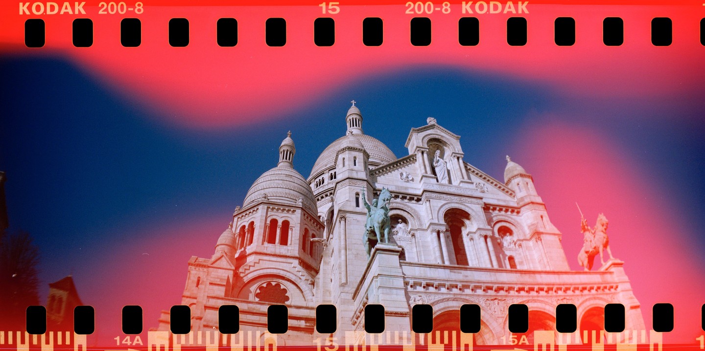 The Sacre-Coeur Basilica is visible against a blue sky with red light leaks.