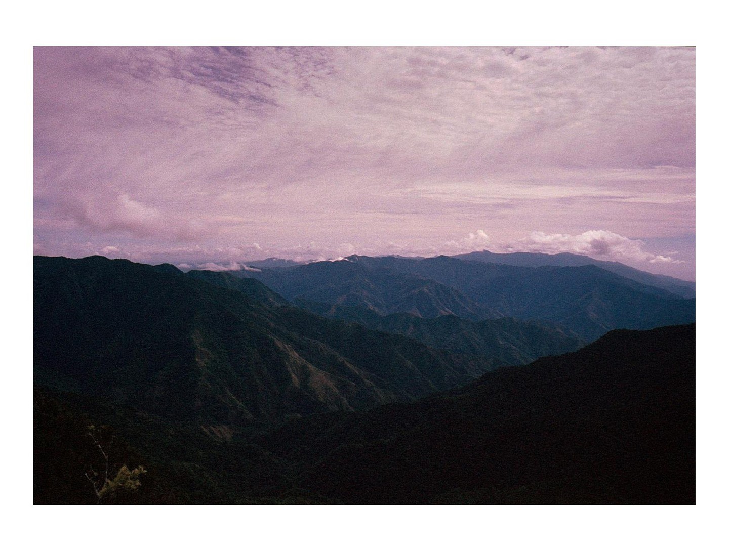 The sun sets over the Sierra Maestra mountains in Cuba, with a purple sky and clouds.