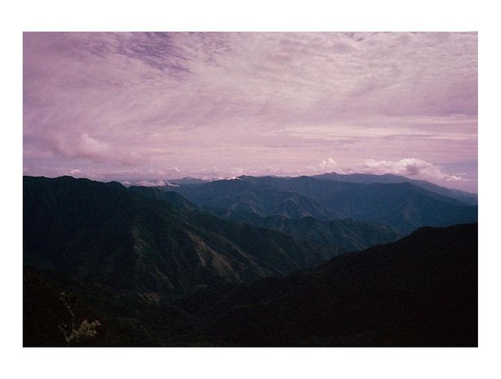 The sun sets over the Sierra Maestra mountains in Cuba, with a purple sky and clouds.