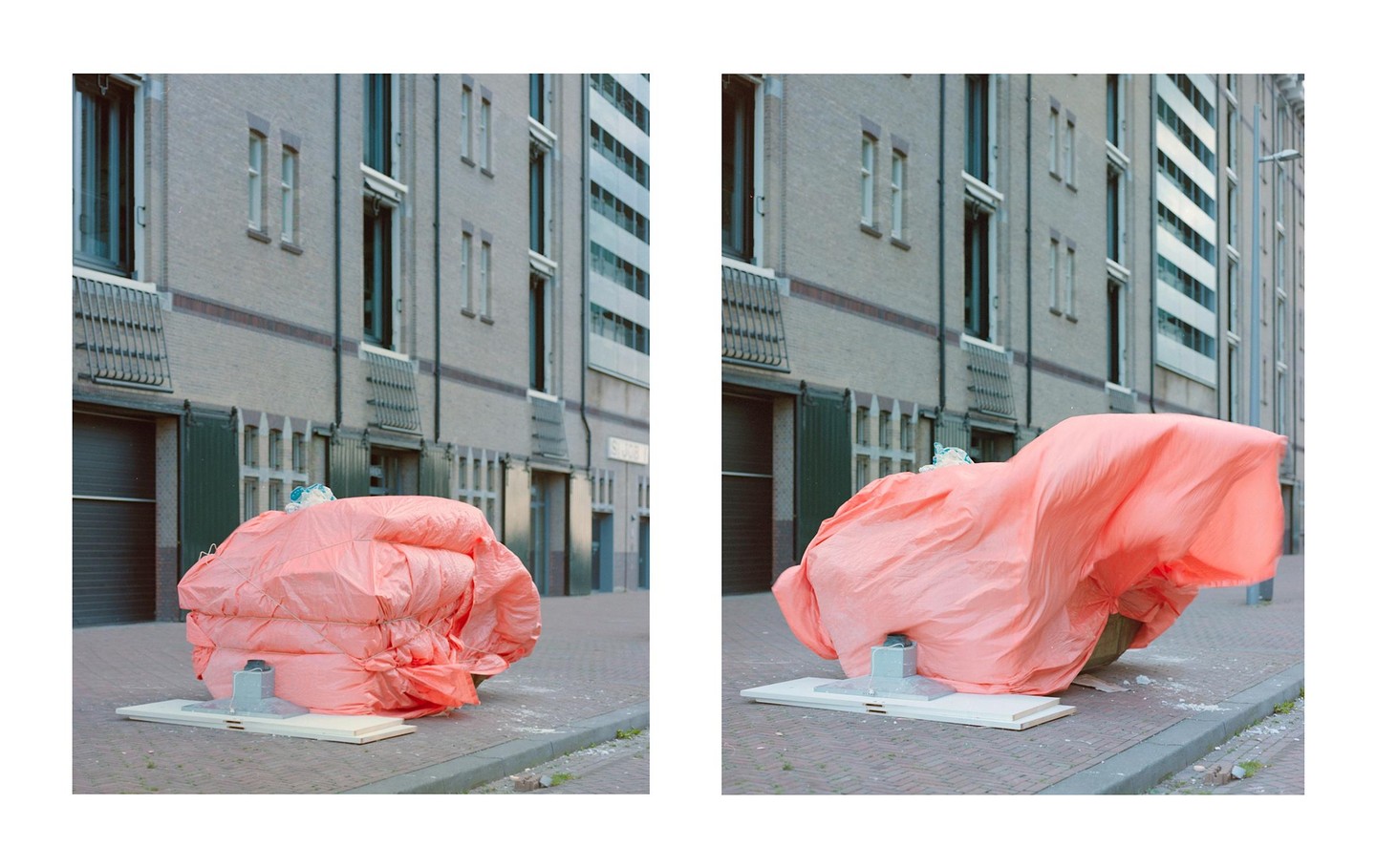 A large pink tarp covers an object on a city street, with a building in the background.