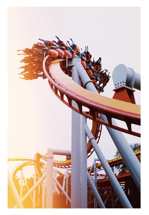 A roller coaster full of people is captured mid-ride against a bright sky.