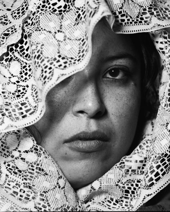 A woman's face is partially obscured by a lace veil.