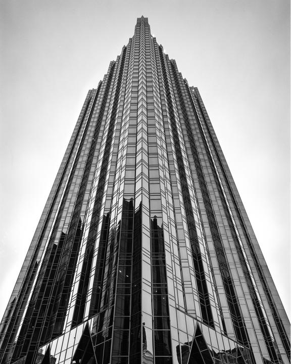 A tall, pointed skyscraper with many windows reflects its surroundings.