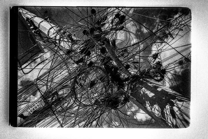 A utility pole is covered in a dense tangle of wires and cables.