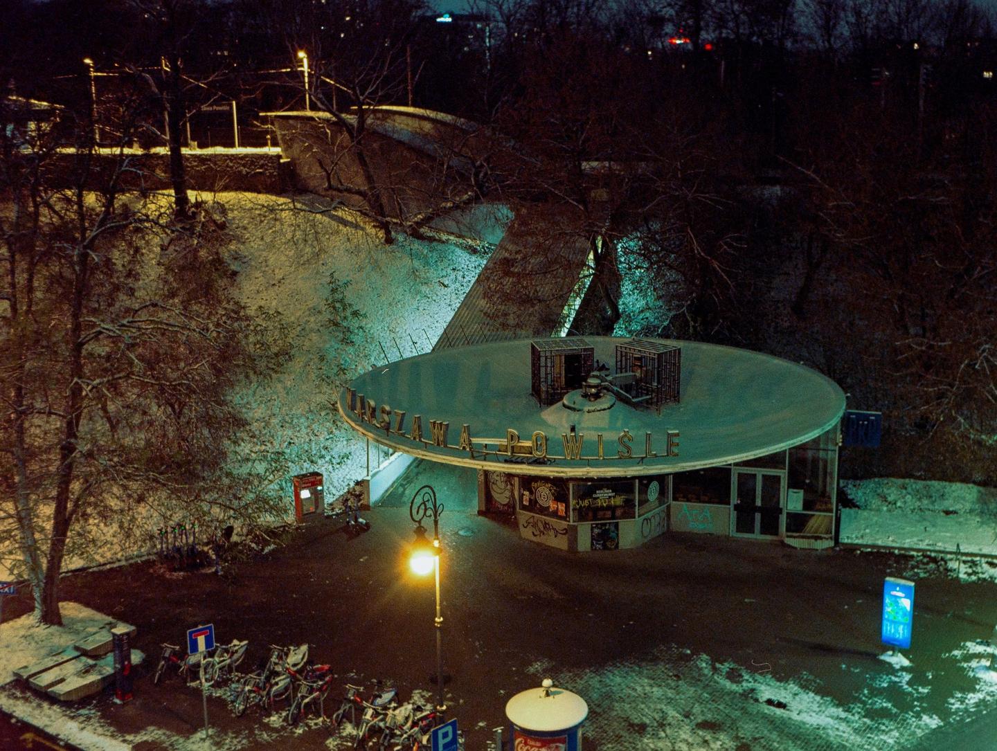 A snow-covered building with a circular roof and the word "POWISLE" on it is illuminated at night.