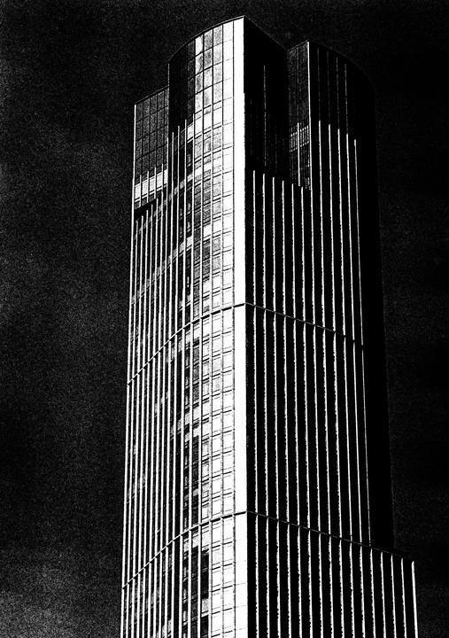 A tall building with many windows is shown against a dark sky.