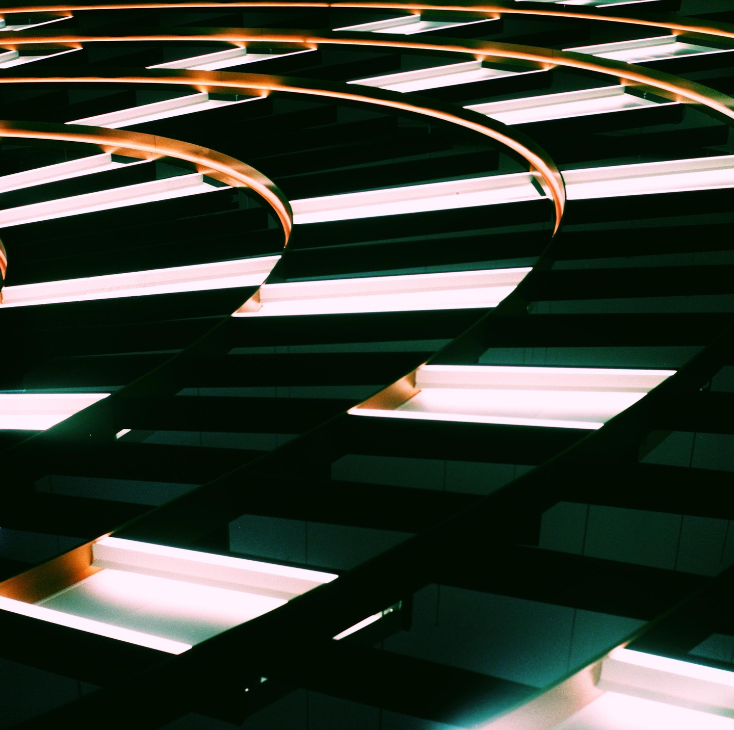 A pattern of illuminated rectangular lights and curved orange beams creates an abstract composition.