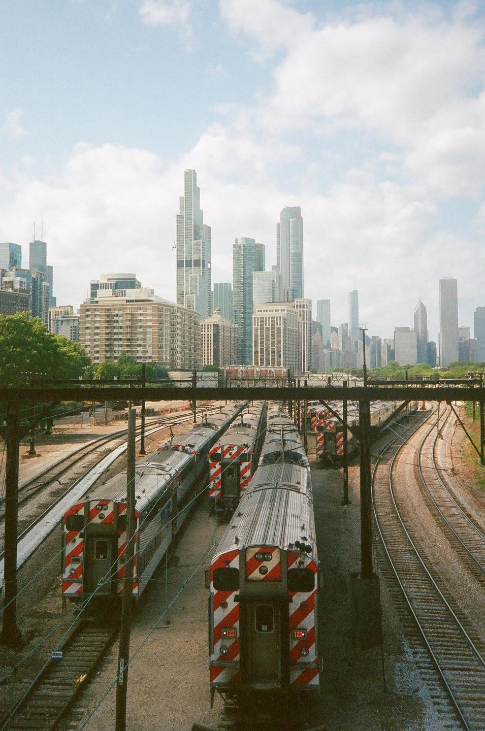 Several trains are parked on tracks with a city skyline in the background.