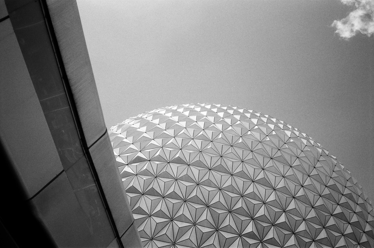 A geodesic dome with a triangular pattern is visible against a clear sky, with a building edge on the left.