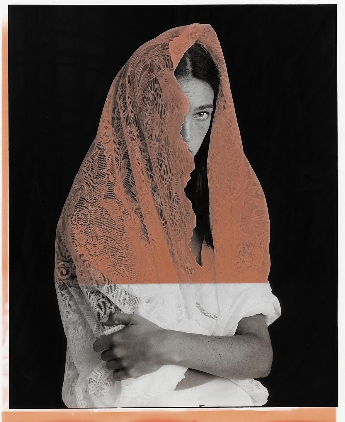 A woman with long hair is partially covered by a lace veil, with one eye visible.