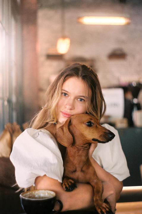 A woman holds a dachshund in a cafe.