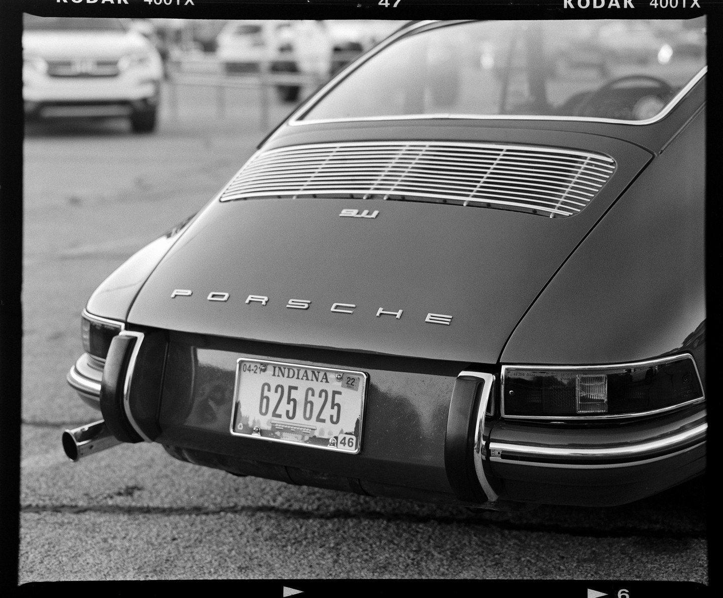 The rear of a Porsche 911 is visible with an Indiana license plate.