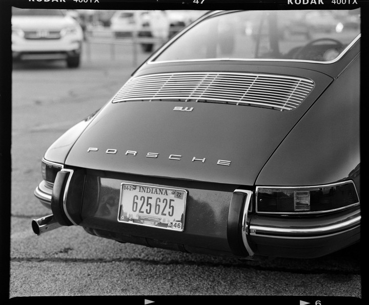 The rear of a Porsche 911 is visible with an Indiana license plate.