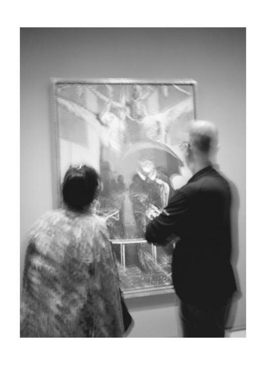 A man and a woman stand in front of a painting in a museum.