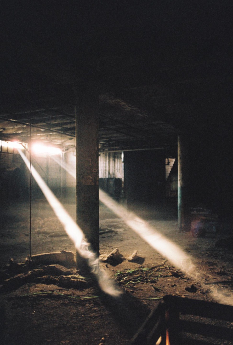 Sunlight streams through a dusty, dark, and abandoned interior space.