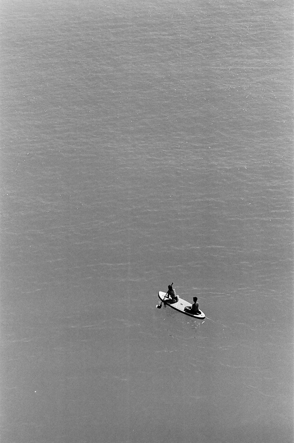 Two people are on a paddleboard in the middle of a vast expanse of water.