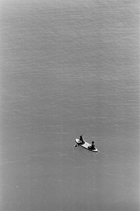 Two people are on a paddleboard in the middle of a vast expanse of water.