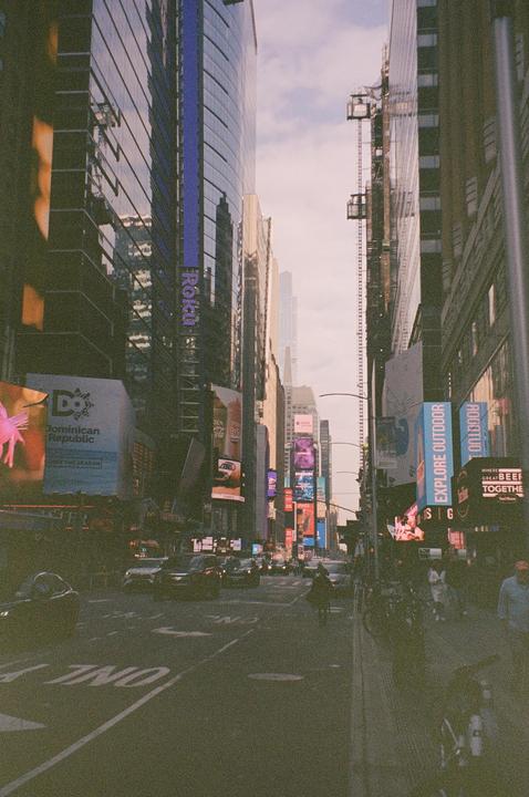 A street in New York City is lined with tall buildings and bright billboards.