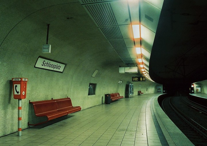 A subway platform with red benches and an emergency phone booth is visible next to train tracks.