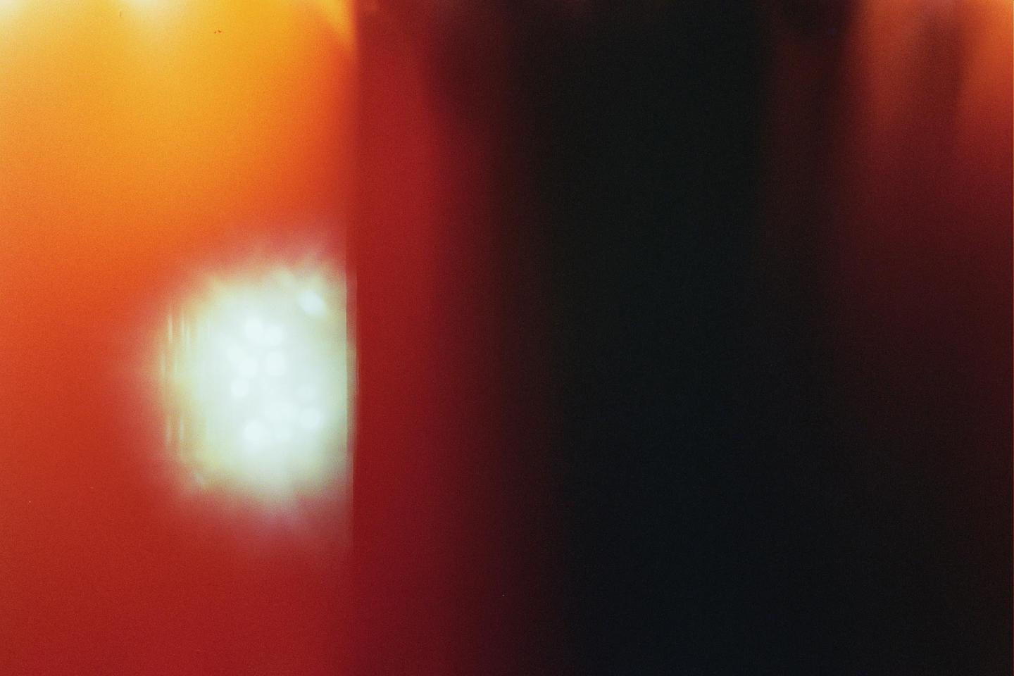 A bright light leak appears on the left side of the frame, with a gradient of orange and red fading into darkness on the right.