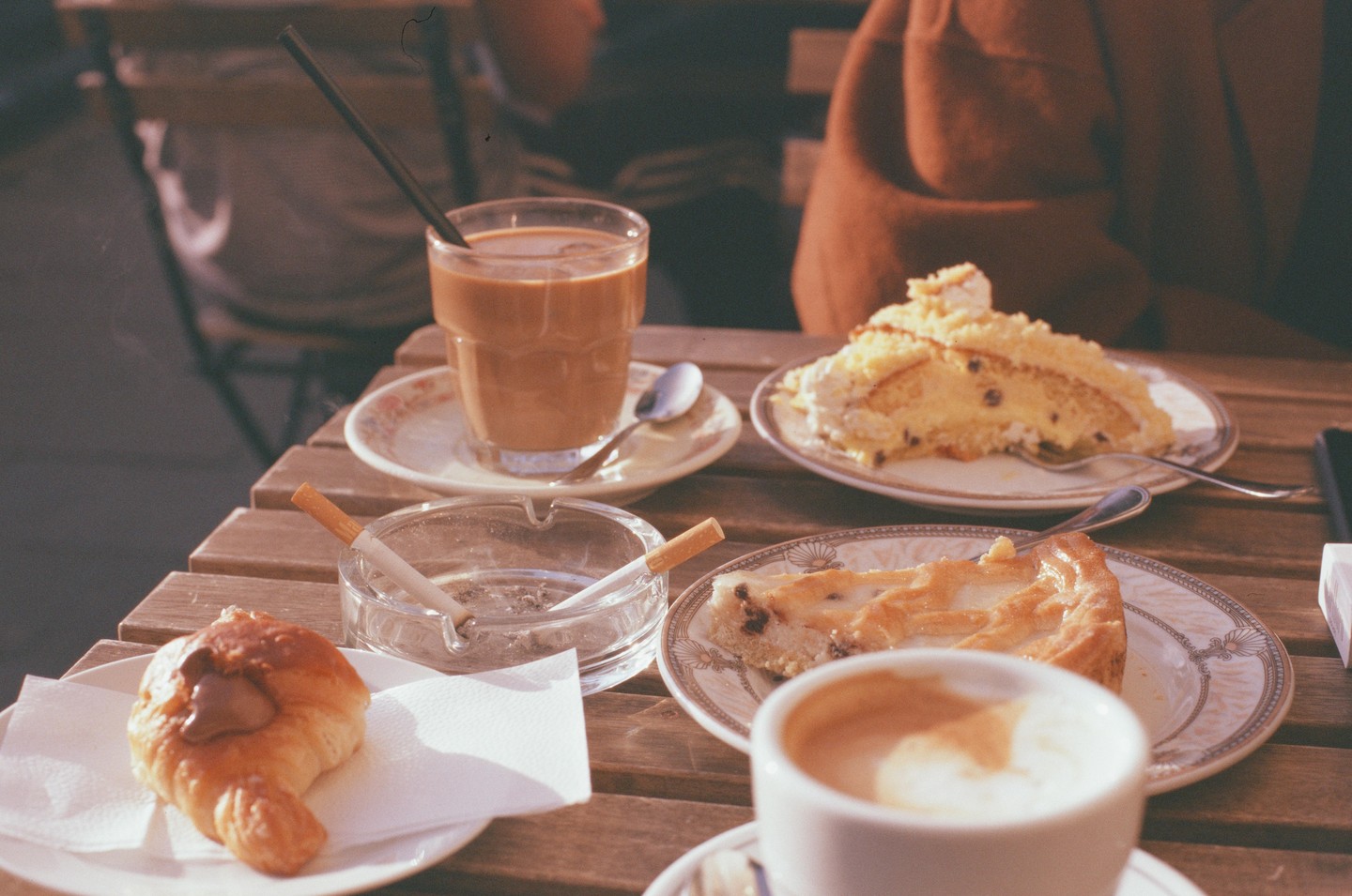 A table is set with coffee, pastries, and an ashtray with cigarettes.