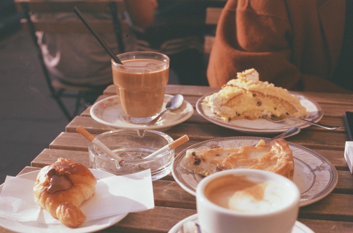 A table is set with coffee, pastries, and an ashtray with cigarettes.
