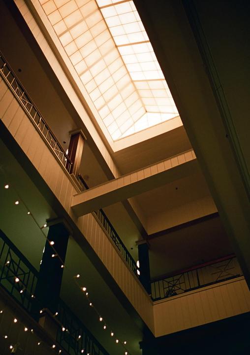A low-angle view shows the interior of a building with multiple levels, balconies, and a large skylight.
