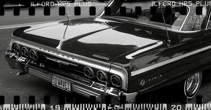 The rear of a Chevrolet Impala is visible, with its taillights and bumper reflecting light.