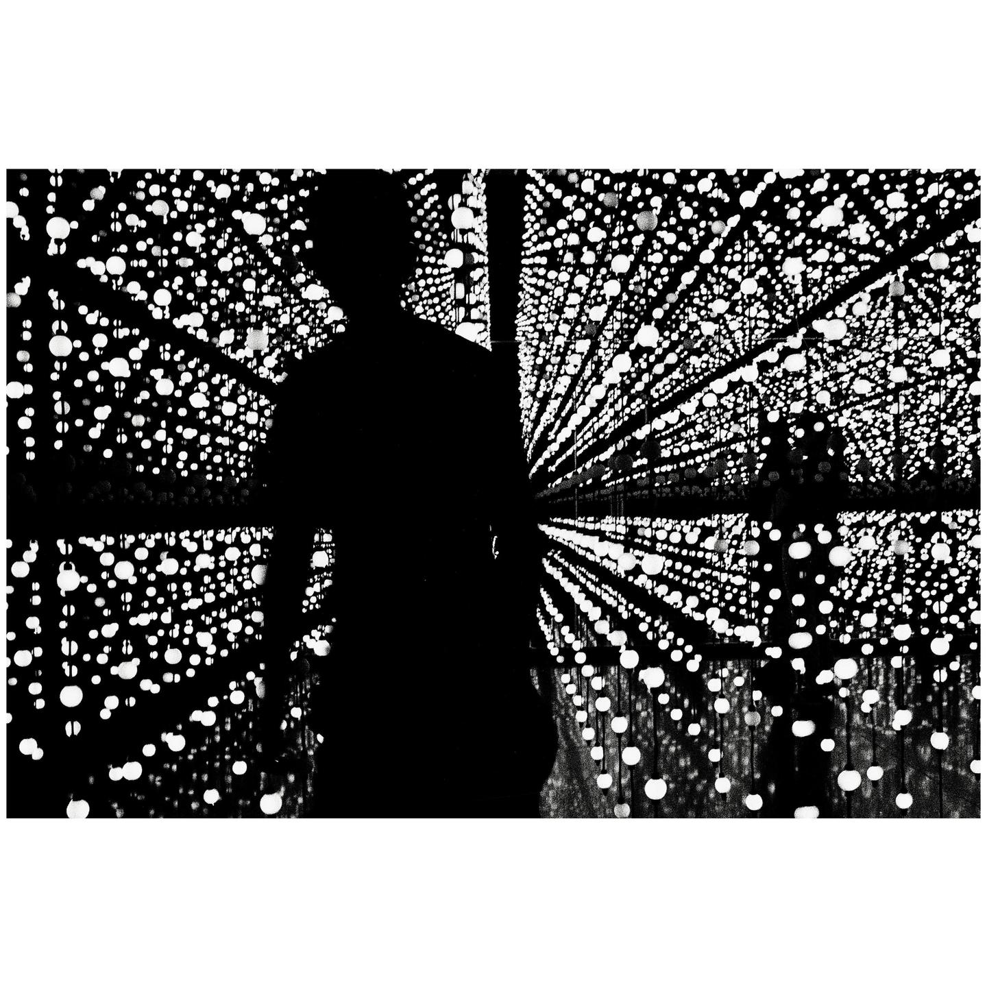 A silhouette of a man stands in a room filled with glowing orbs.