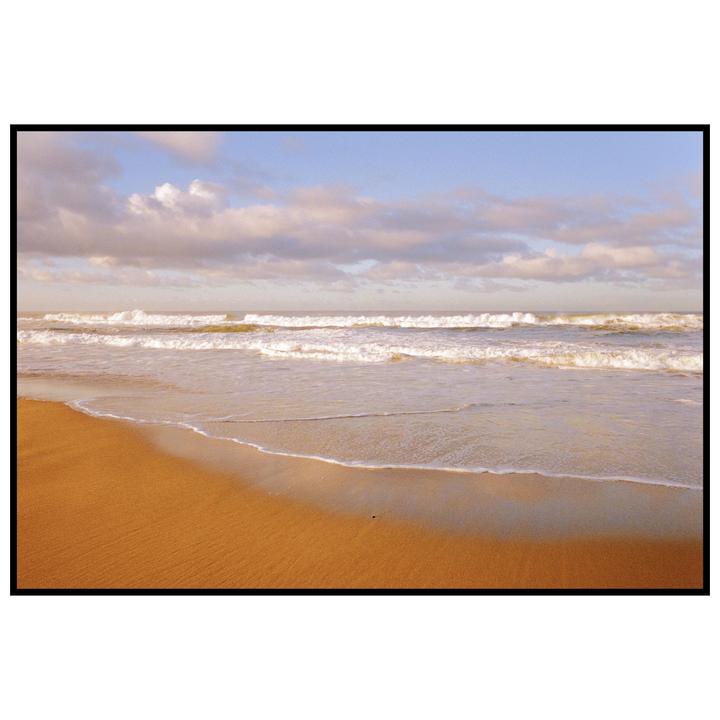 Waves crash on a sandy beach under a cloudy sky.