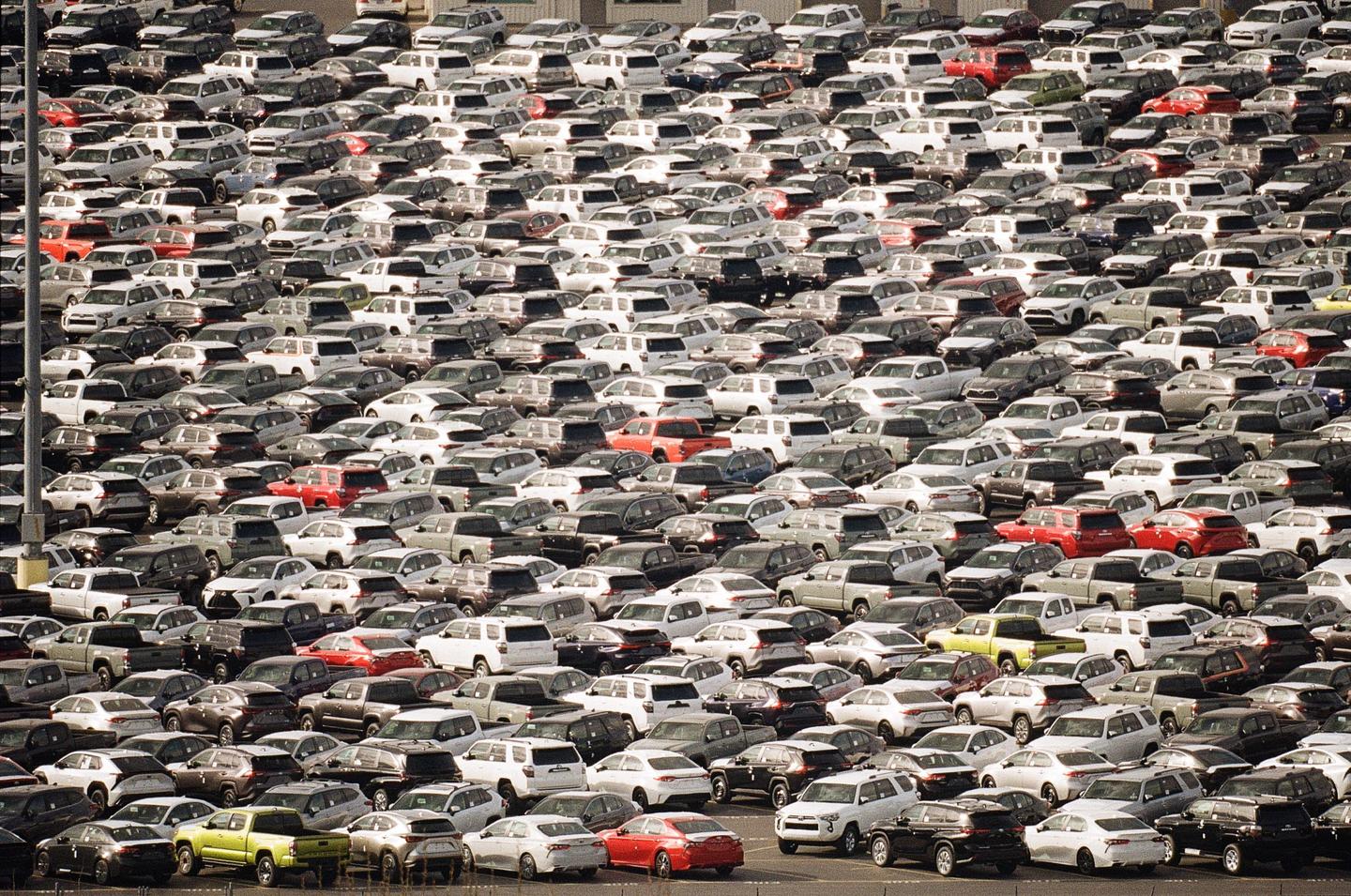 Hundreds of cars are parked closely together in a large lot.