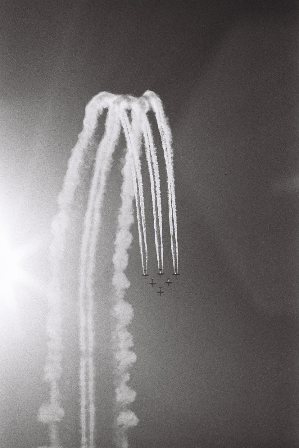 A group of airplanes flies in formation, leaving trails of smoke in the sky.
