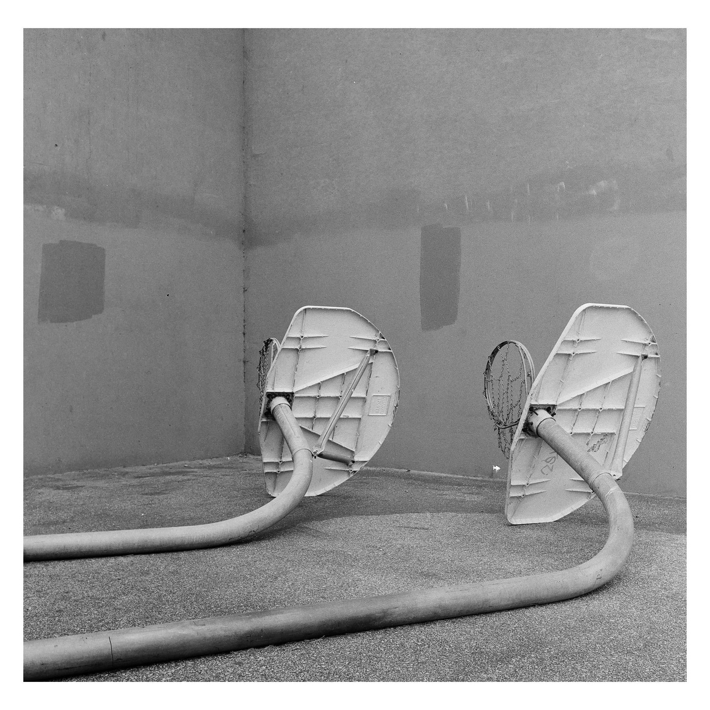 Two broken basketball hoops lie on the ground against a wall.