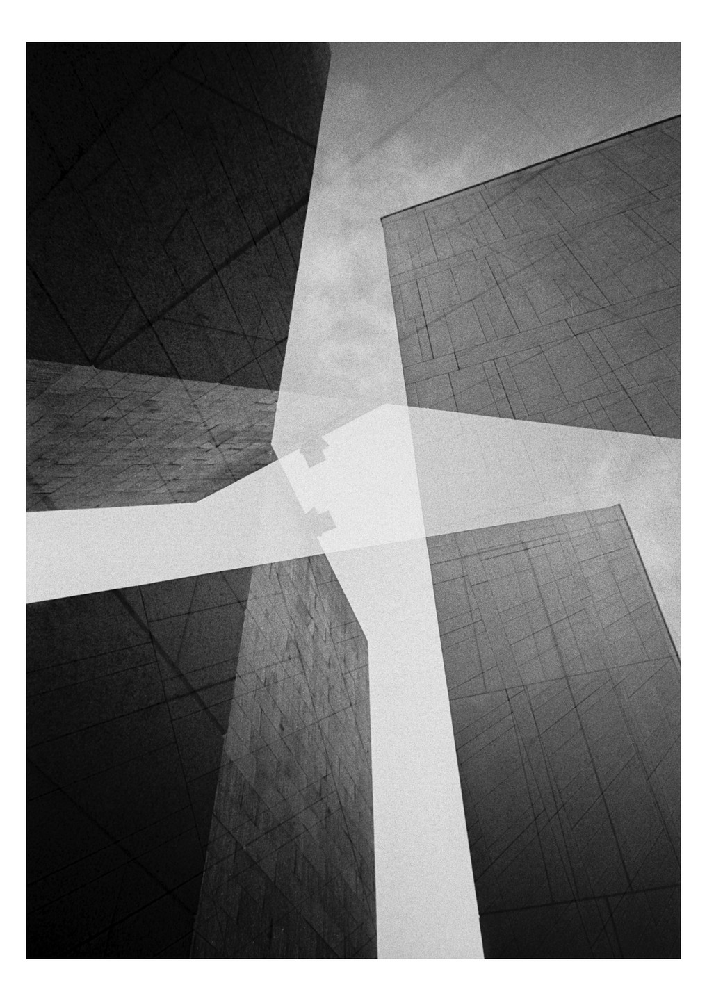 Four tall buildings are visible from a low angle, with a white cross shape superimposed over them.