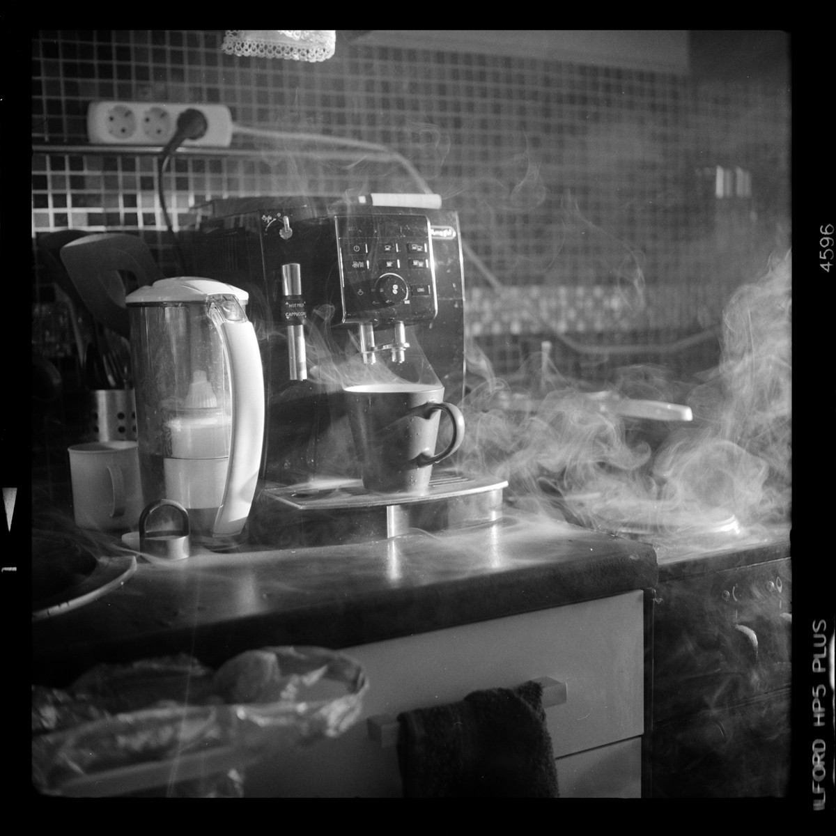 A coffee machine steams a mug on a kitchen counter next to a water filter.