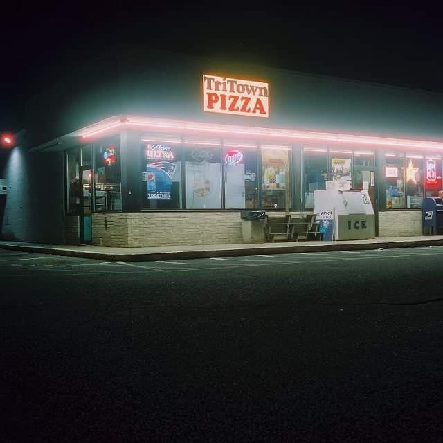 A pizza shop with a neon sign is illuminated at night.