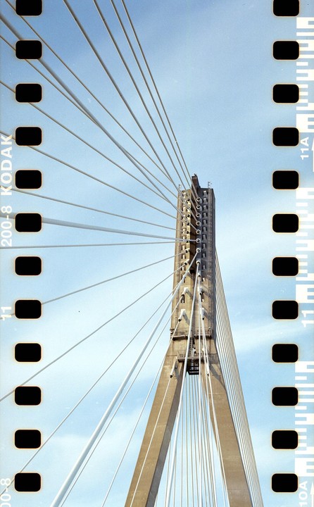A low angle view shows the concrete tower and cables of a suspension bridge against a clear sky.