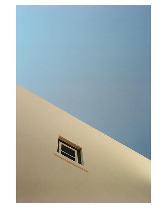 A small window is visible on a beige building against a clear blue sky.